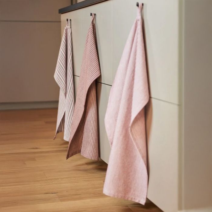 3 bolsjestribede viskestykker i røde nuancer hængende i stropper