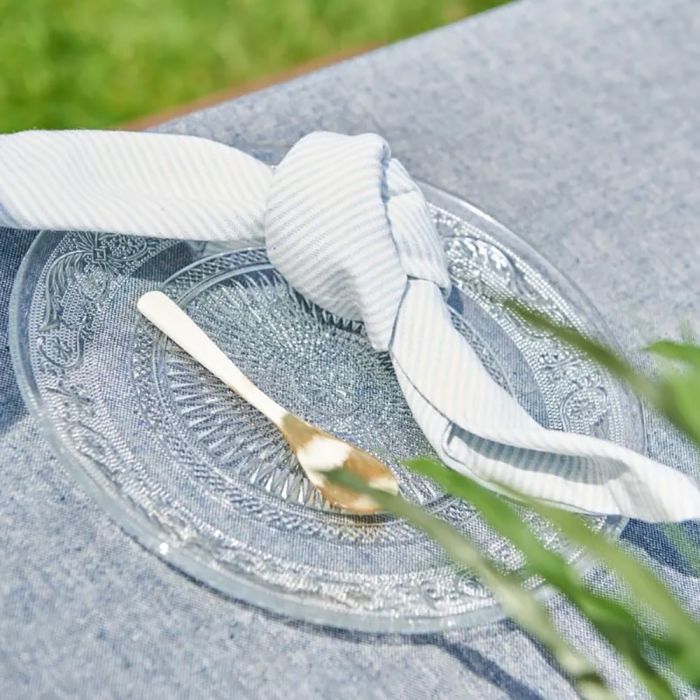 Speedtsberg stofserviet med lyseblå striber bundet i knude på en glastallerken