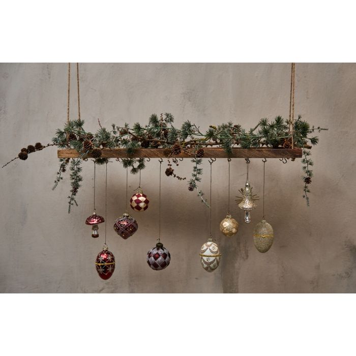 Svævehylde pyntet med cedertræranke og glaskugler.