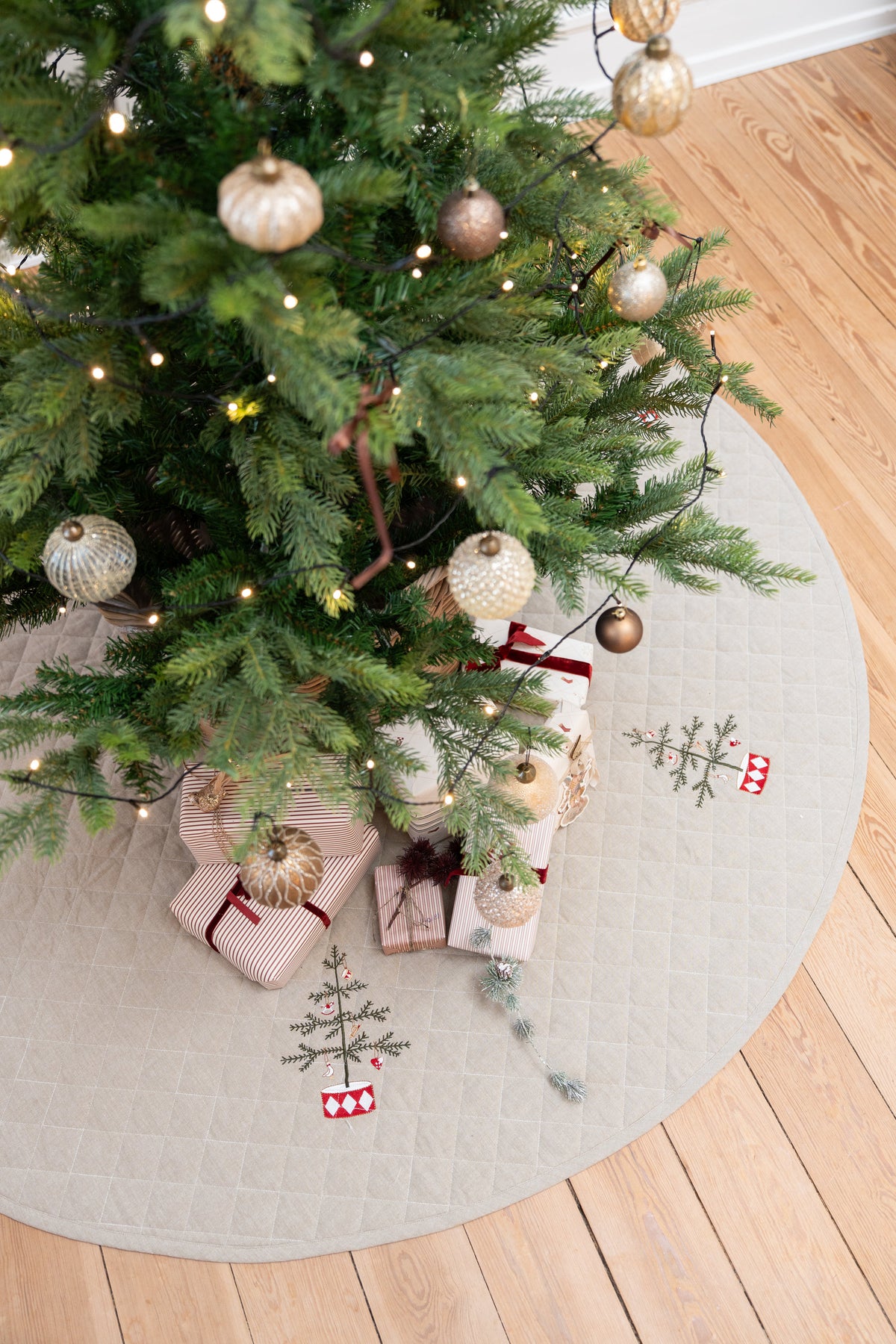 Pyntet juletræ stående på quiltet juletræstæppe med broderi på fra Speedtsberg