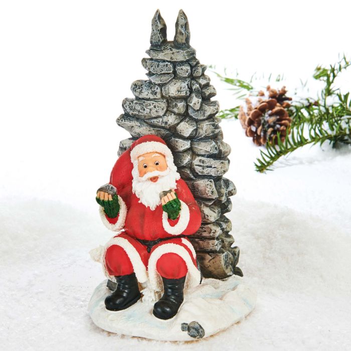 Julemanden sidder på en isflage op af en stenvæg med ønskesten i hver hånd. Julemanden er fra Pobra.