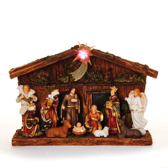 Krybbespil foran flot træagtig bygning med stjerne på taget med lys i. Til stede er Josef og Jomfru Maria med det lille Jesus barn samt de 3 vise mænd, Kejser Augustus og en smuk engel. Fra Pobra.