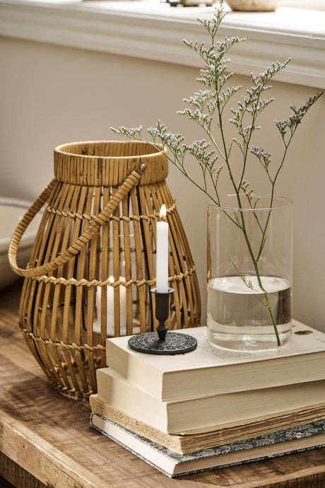 Lanterne og bøger med cylinderglasvase med blomster ovenpå