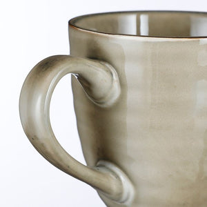 Nærbillede af hank på Tabo stentøjskrus i creme