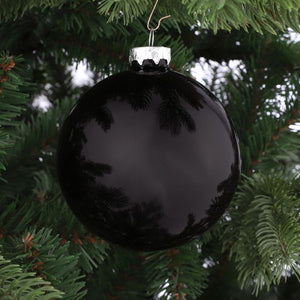 Sort blank julekugle i glas på juletræ. Reflekterende overflade med spejleffekt giver et eksklusivt look til julepynten.