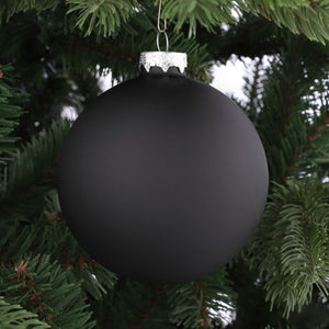 Mat sort julekugle i glas hænger på juletræ. Den matte overflade giver et elegant og tidløst udtryk.