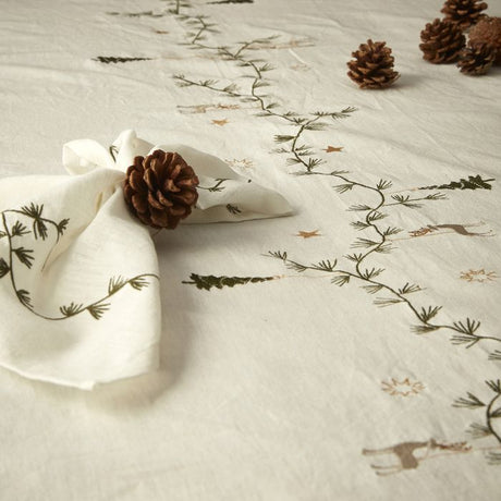 Stofservietter vinter på bord med grankogler og dug