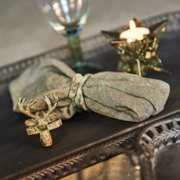 Servietring i antik grøn på stofserviet med servietring formet som hjort i forgrunden