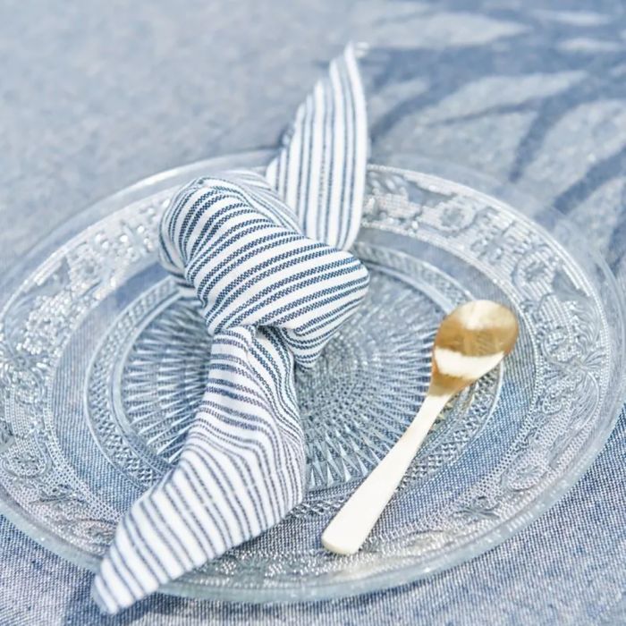 Speedtsberg stofserviet med mørkeblå striber bundet i knude på glastallerken