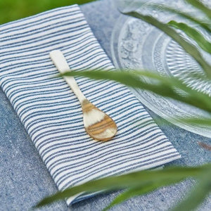 Speedtsberg stofserviet med mørkeblå striber foldet med en guldske ovenpå