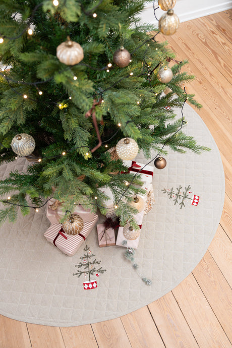 Pyntet juletræ stående på quiltet juletræstæppe med broderi på fra Speedtsberg