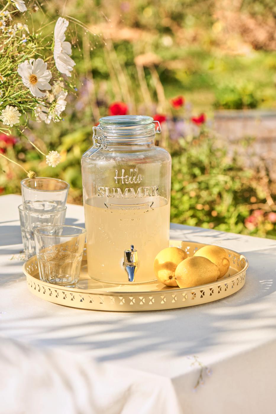 Saftdispenser med tappehane i klart glas fyldet med saft