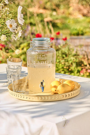 Saftdispenser med tappehane i klart glas fyldet med saft