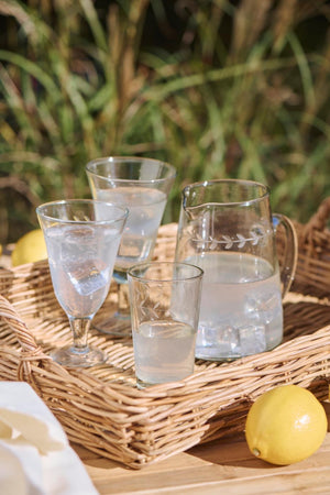 Aflang bakke i rattan med hanke fra Ib Laursen med glas og kande på