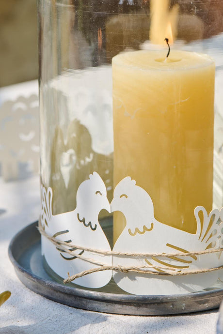 Påskebordpynt høns rundt om et cylinderglas med bloklys indeni