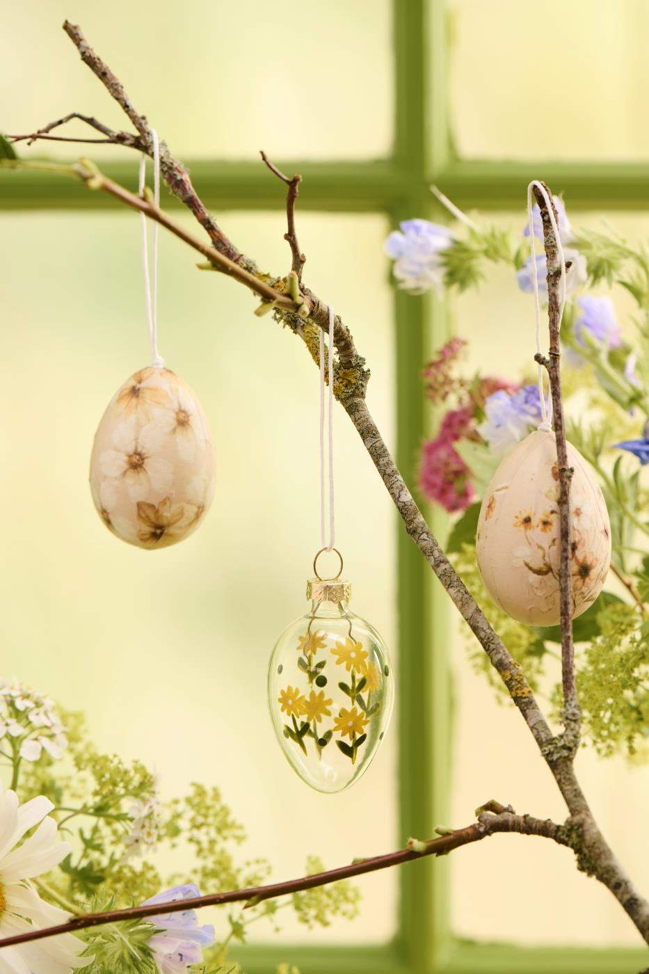 To påskeæg i glas med blomster fra Ib Laursen hænger på en gren