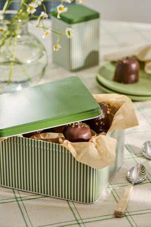 Dåse med grønne og hvide striber og grønt låg fyldt med chokolader