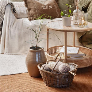 Ib Laursen opbevaringskurv i pil med to hanke med strikketøj på gulv ved sofabord og stor vase