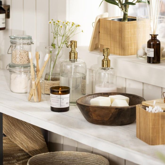 Ib Laursen ALTUM Meadow duftlys i brunt glas på hvid hylde med andre badeværelsesprodukter