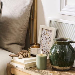 Ib Laursen ALTUM Meadow duftlys i brunt glas på sengebord ovenpå bøger